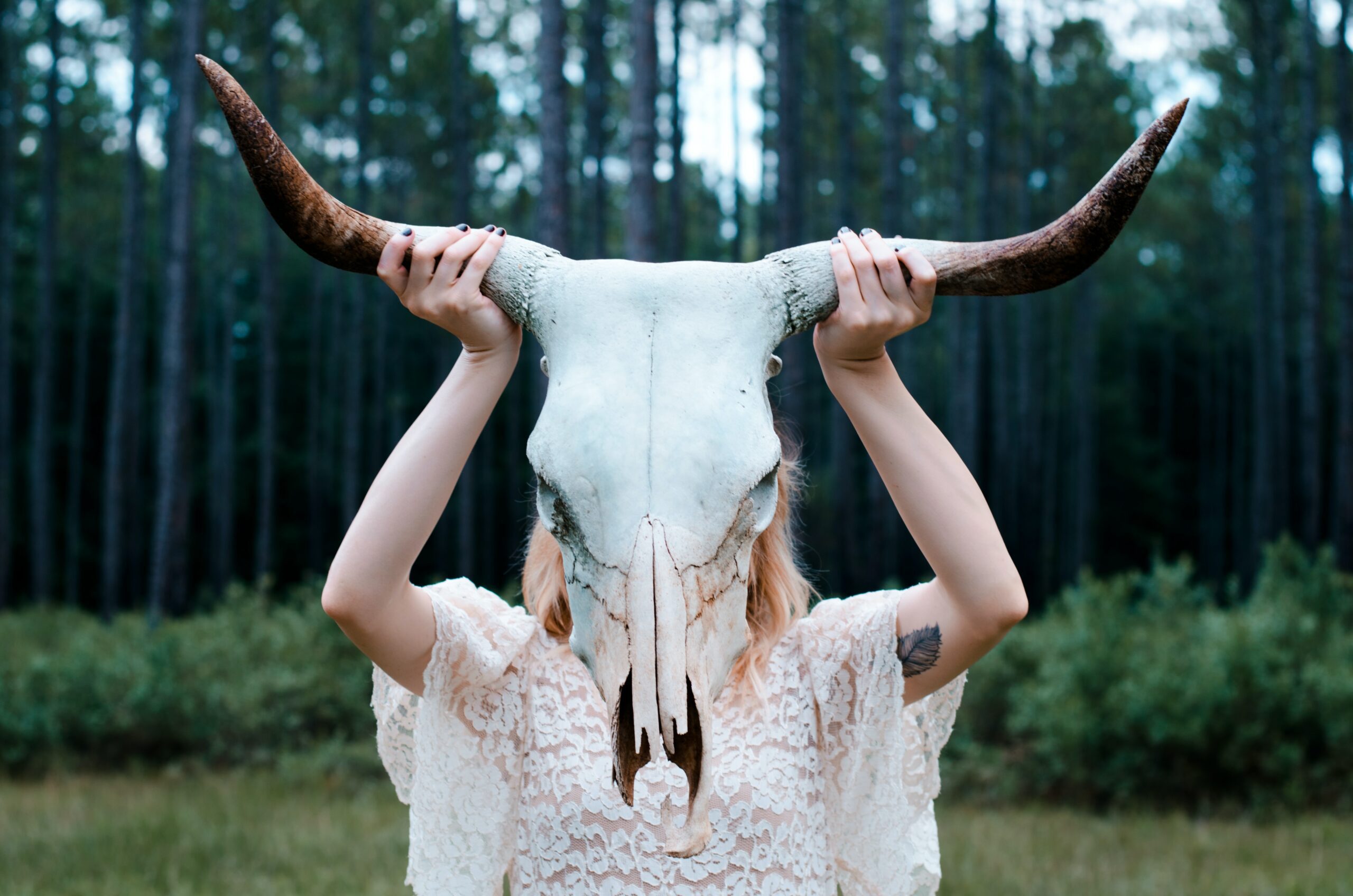 A woman holding up a skull with horns.